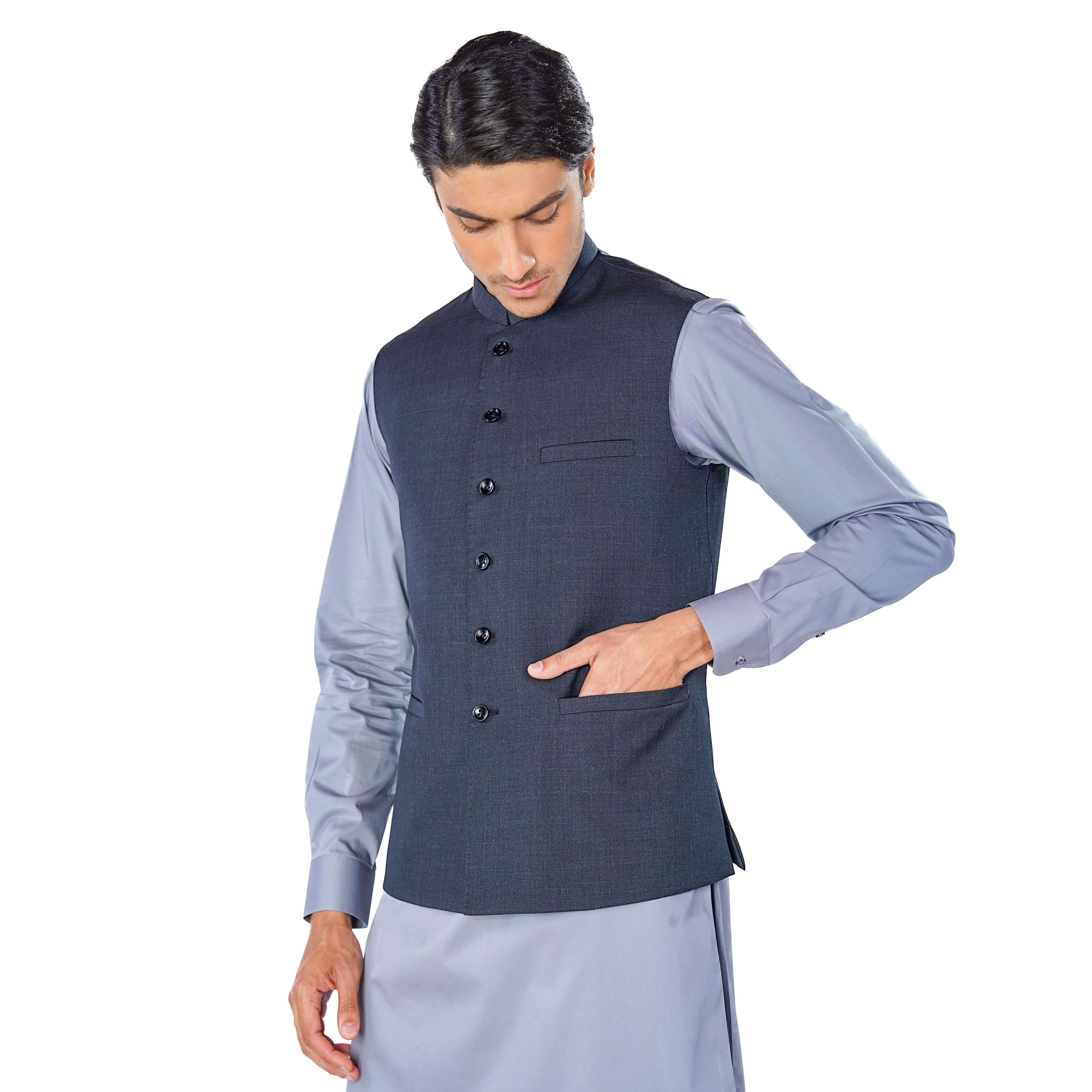 Man wearing a dark gray vest over a light blue shirt on a white background