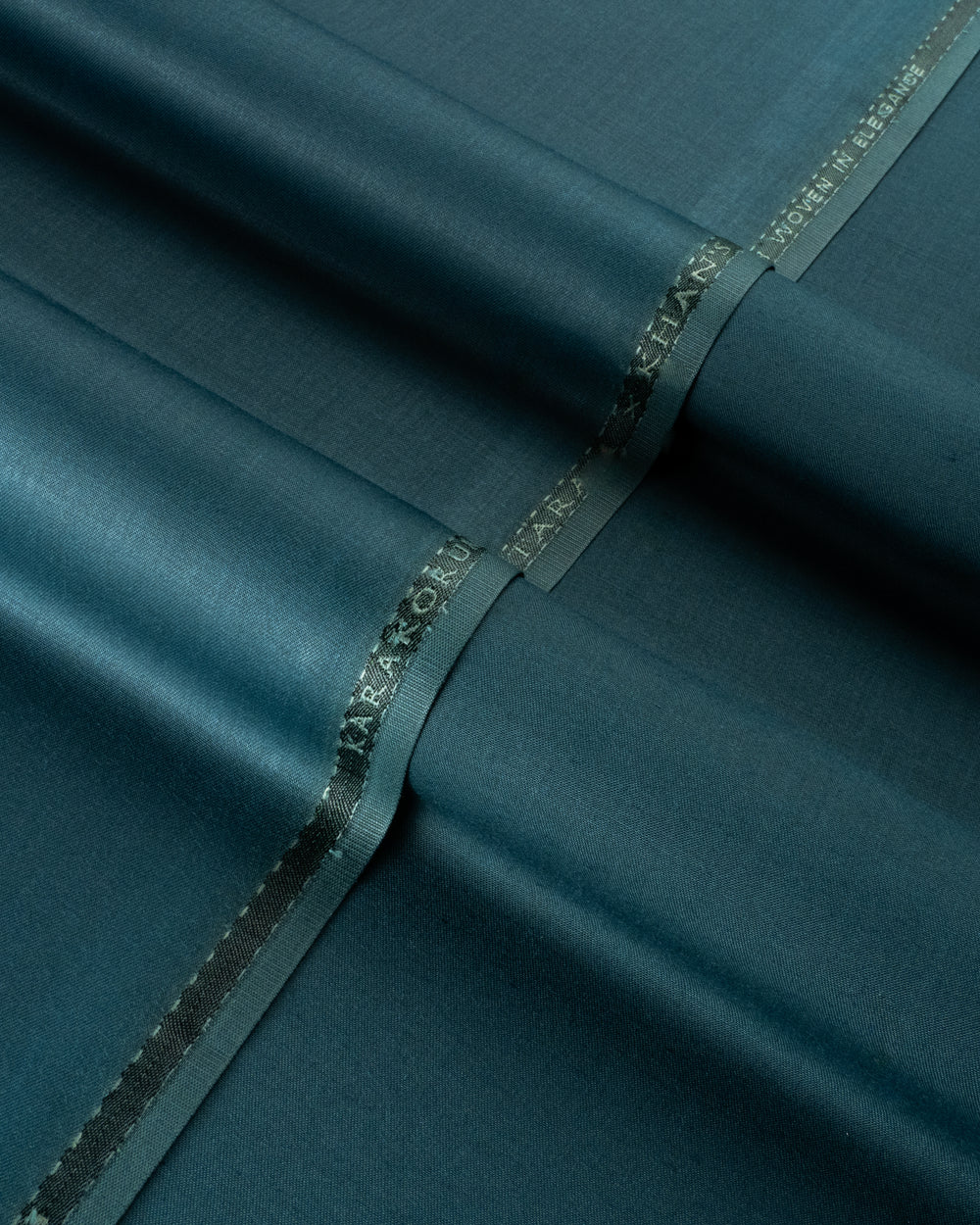 Teal fabric with a brand label on a dark teal background