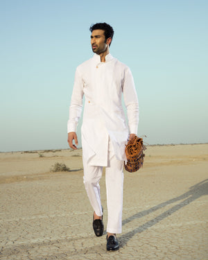 Man in a white traditional outfit standing in a desert landscape