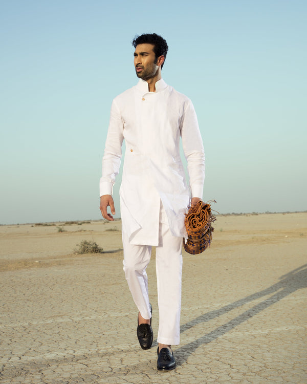 Man in a white traditional outfit standing in a desert landscape