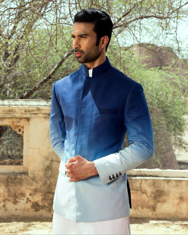 Man in traditional outfit standing in front of an old fort.