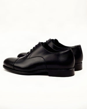 Pair of black leather dress shoes on a white background