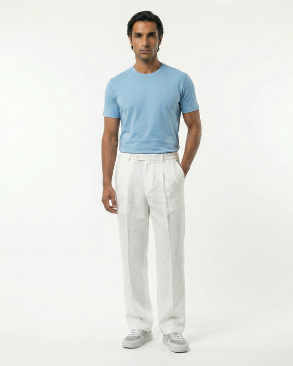 Man wearing a light blue shirt and white pants on a white background