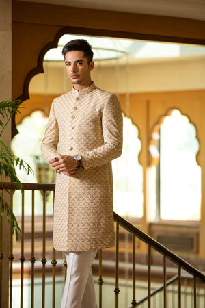 Man wearing a beige kurta with white pants in an elegant interior setting
