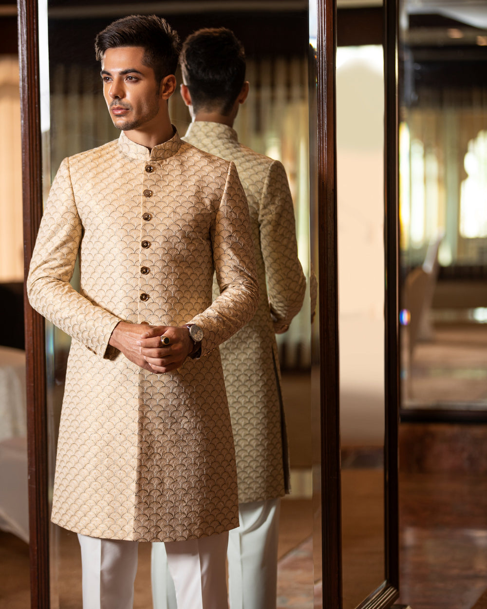 Man wearing a traditional beige sherwani in an indoor setting