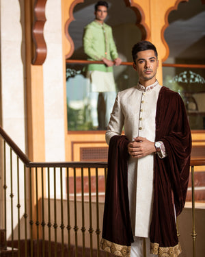 Man wearing a traditional outfit with a decorative background