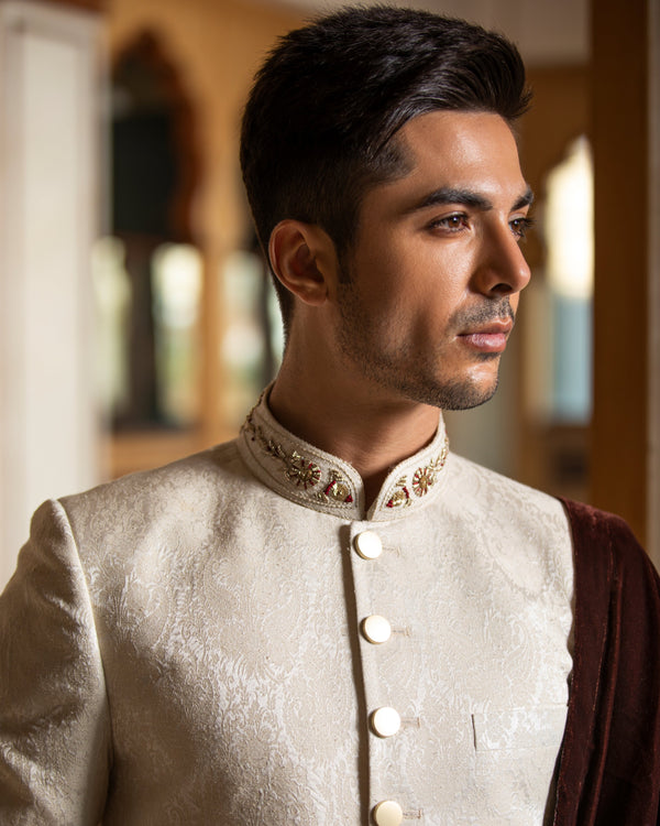Man wearing a traditional embroidered sherwani in an indoor setting