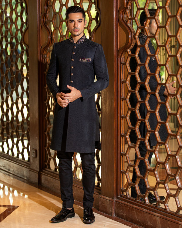 Man wearing a dark blue kurta with a patterned wooden door in the background