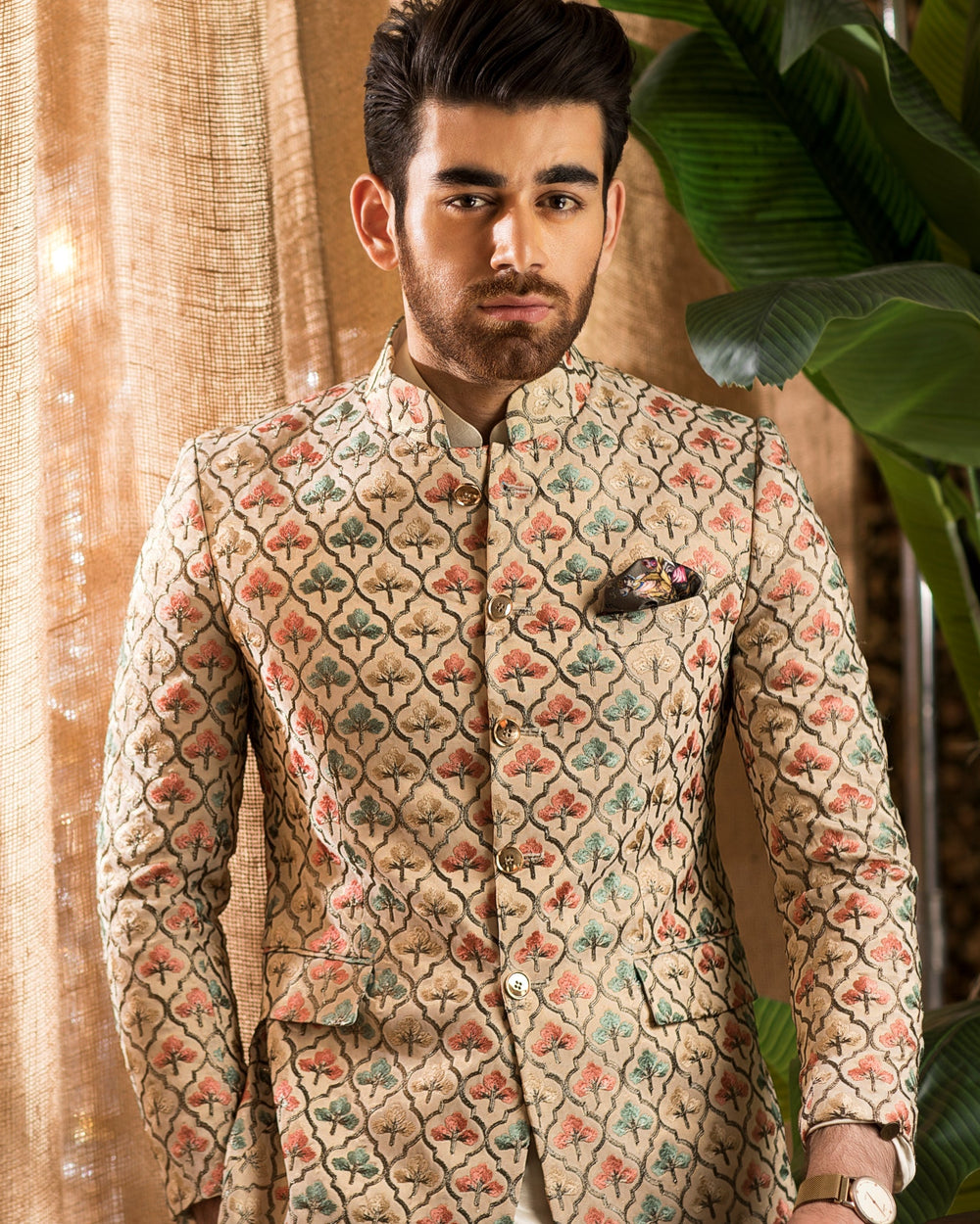 Man in traditional attire standing next to a brown leather chair with decorative elements.