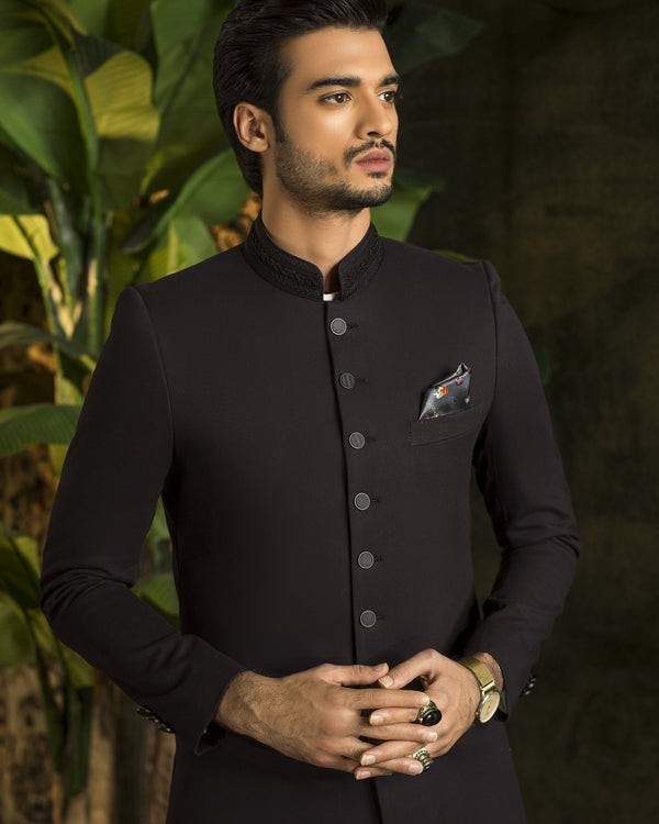 Man wearing a black traditional outfit with a dark background