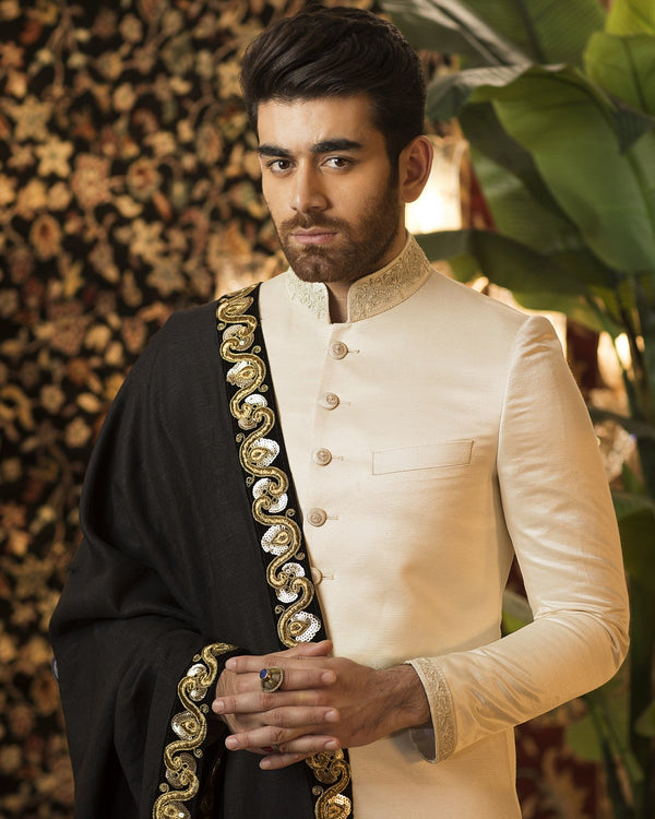 Man wearing a traditional outfit with decorative elements in a decorated indoor setting