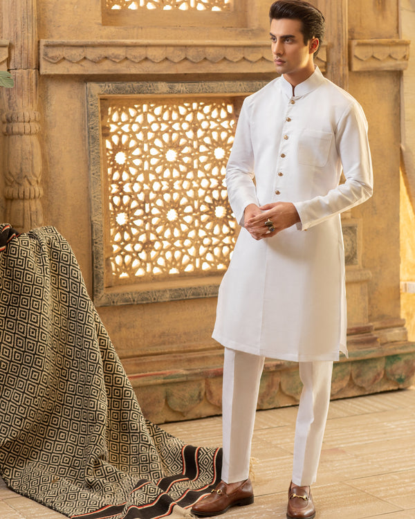 Man wearing a white kurta with a wooden lattice background