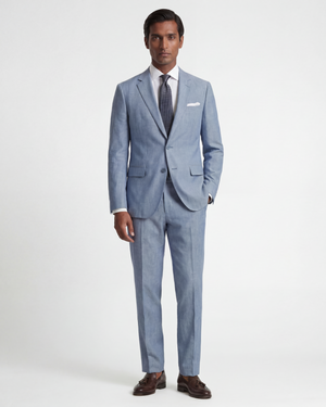 Man wearing a light blue suit with a white shirt and brown shoes on a white background