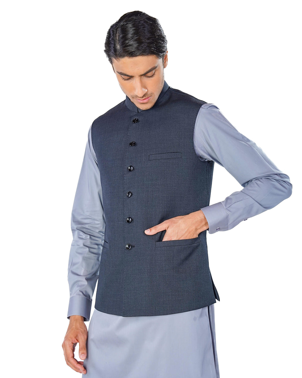 Man wearing a dark gray vest over a light blue shirt on a white background