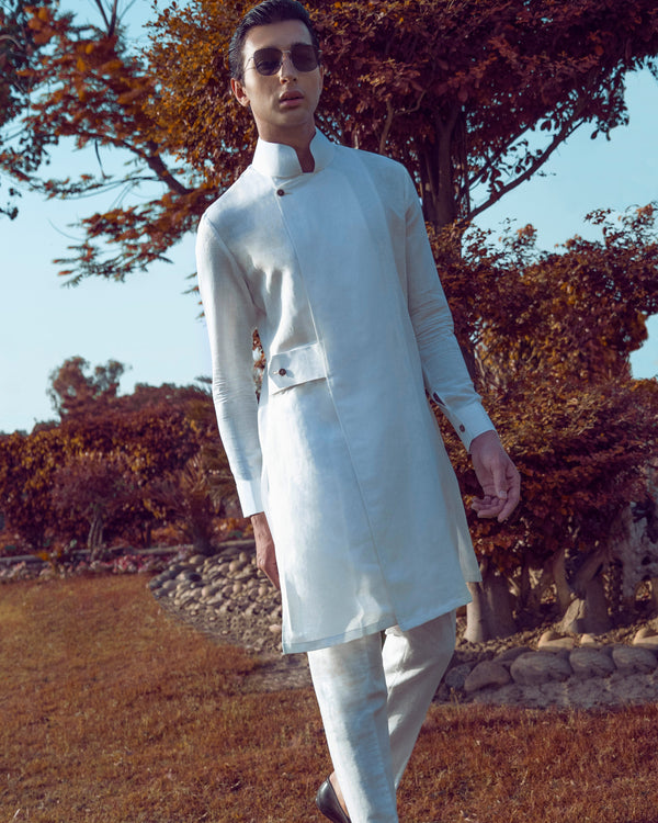 Man in a white kurta standing outdoors with trees in the background