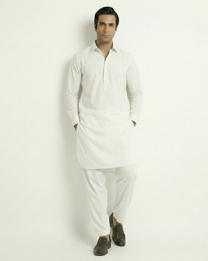 Man wearing a white kurta with white pants on a light gray background