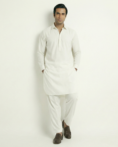 Man wearing a white kurta with white pants on a light gray background