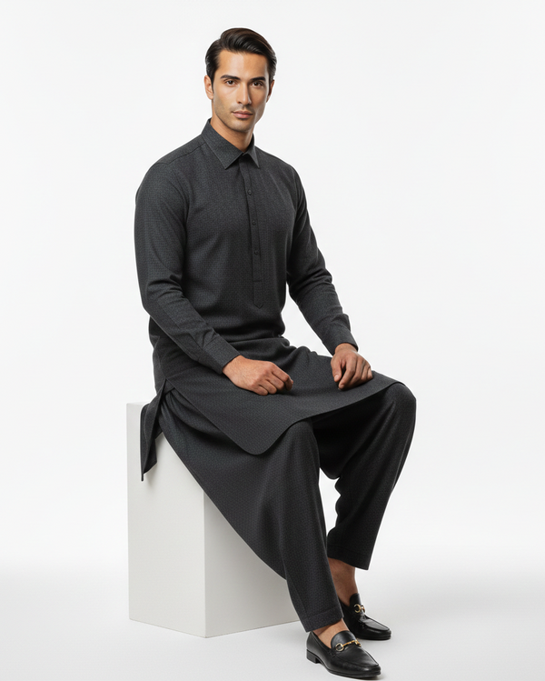 Man wearing a dark gray outfit sitting on a white block against a white background