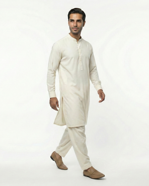 Man wearing a traditional cream kurta with white pants on a white background