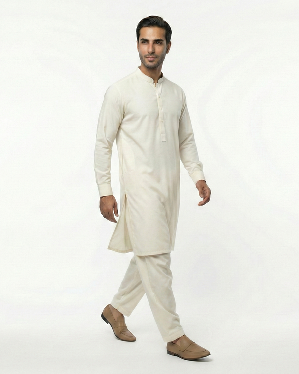 Man wearing a traditional cream kurta with white pants on a white background