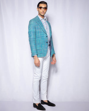 Man wearing a blue checkered blazer, white shirt, white pants, and black shoes on a white background