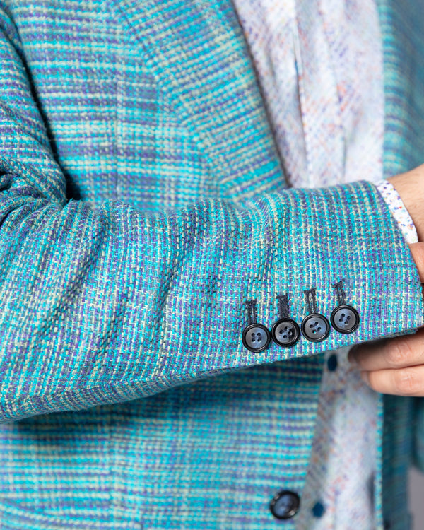 Close-up of a person wearing a blue textured jacket with button details.
