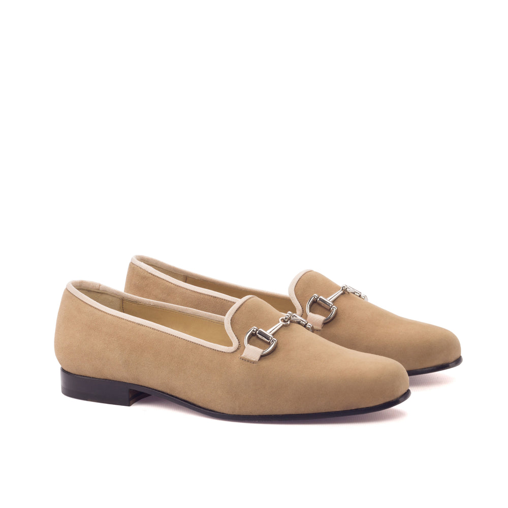 Pair of beige loafers with silver buckles on a white background