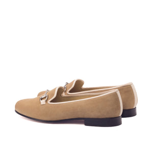 Pair of tan loafers with a decorative buckle on a white background